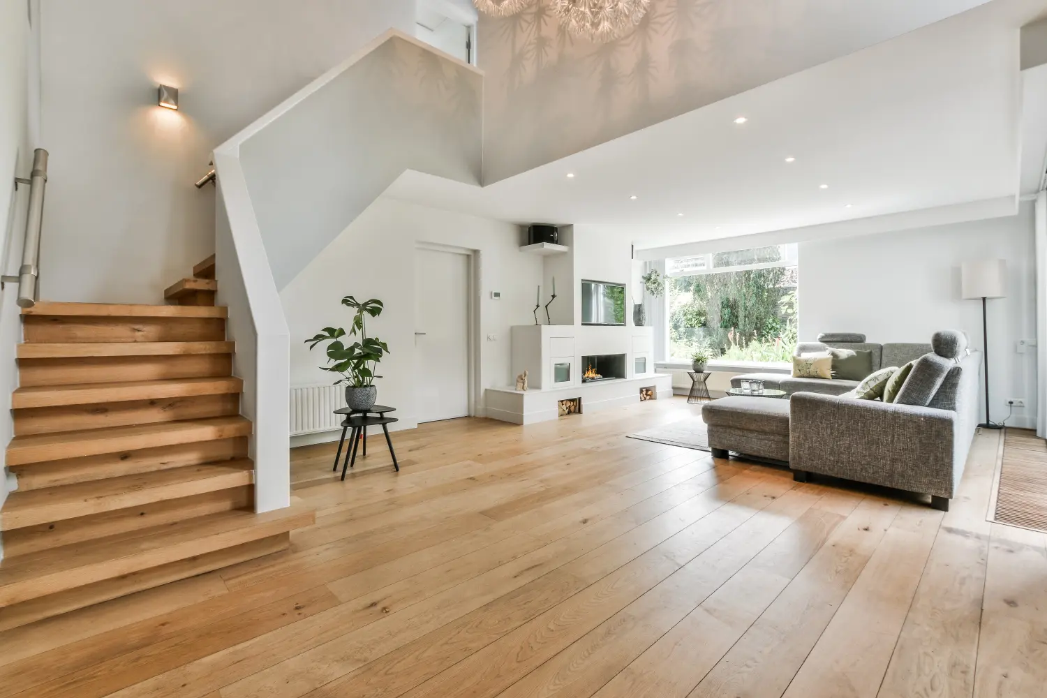 Gemütliches Hausinterieur mit Holzboden, großem grauen Sofa und Treppe zum zweiten Stock